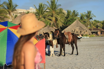 horses and woman with hat on the beach