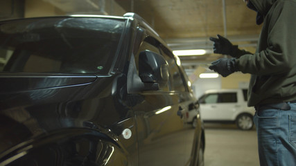 Hacker using a device to open a car in a parking lot