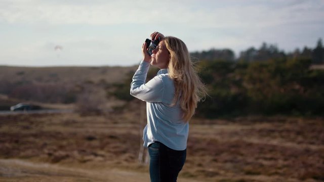 Profile shot of a female photographer taking a photo on a windy day. Slow motion