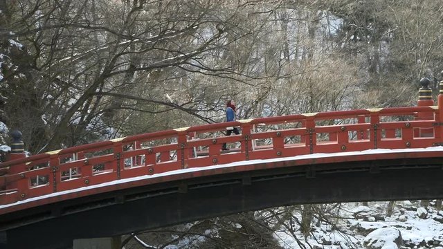 Tracking a lone young woman crossing the snow covered Shinkyo Bridge, Japan