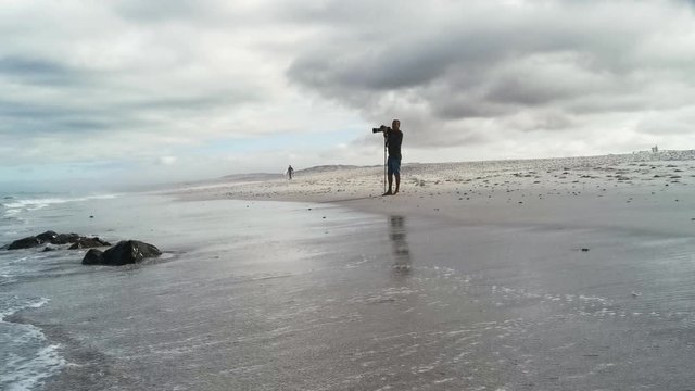 A photographer taking pictures of the ocean from the waters edge