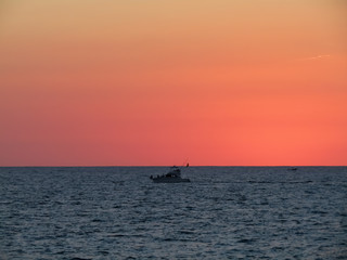 Fototapeta premium Motorboat crosses the sea in a stunning sunset with red sky in Mazatlan Mexico
