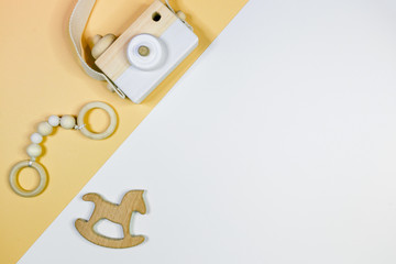 Close up cute nice small wooden baby teethers with different shapes and camera  on yellow background. Eco accessories for newborn, baby. Flat lay, top view