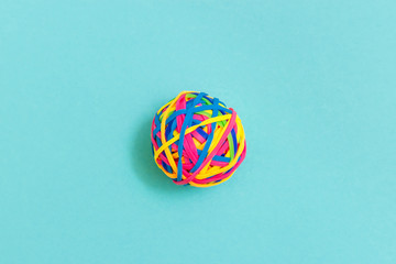 Ball or knot of thin multicolored elastic bands on plain background.