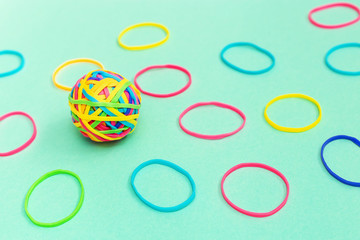 Multicolored rubber ball out of many colorful elastic bands on plain background.