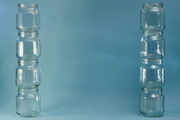 Two wide lined vertical parallel rows of glass jars on a blue background.