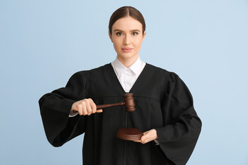 Female judge with gavel on light background