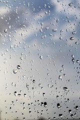 Raindrops on the glass, blurred blue sky.