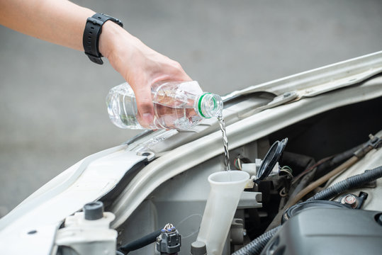 Cropped shot of person hand filling water into car radiator for reduce engine overheating. Engines can overheat because something’s wrong within the cooling system and heat isn’t able to escape.