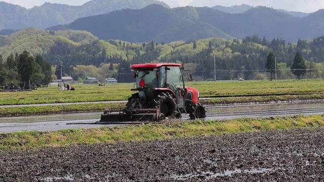 春の農作業風景　農業　田んぼの代掻き　トラクター