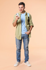 Obraz premium Portrait of male student with mobile phone on color background
