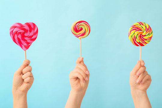 Hands with sweet lollipops on color background - Powered by Adobe