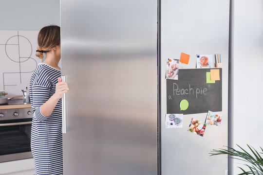 Young Woman Opening Refrigerator In Kitchen