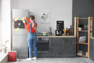 Young woman near refrigerator in kitchen