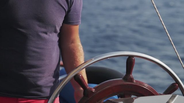 A close up shot of a skipper steering a ship at sea