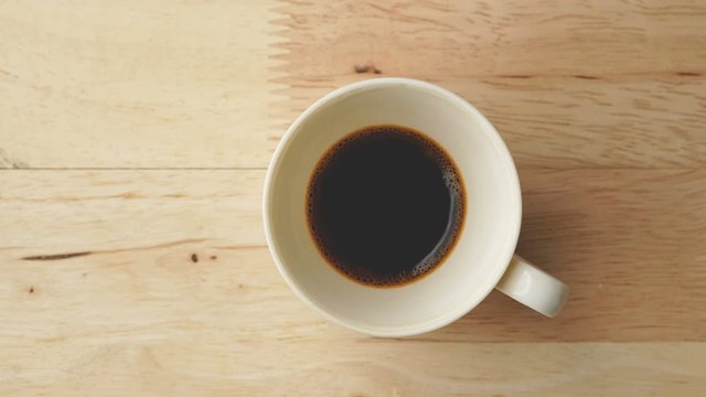 Stop motion drinking hot coffee on wooden table, Top view 