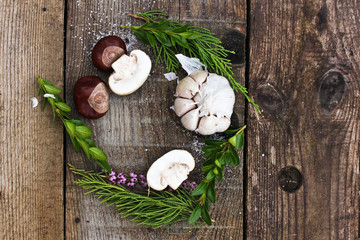 Obraz na płótnie Canvas half of the mushrooms is cut for lunch in the fresh air, lies on a gray board with chestnuts and herbs. Circle frame.