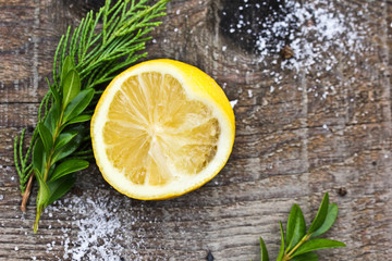 Half sliced lemon with salt and herbs on a dark wooden background. Snack for a drink.
