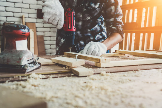 Carpenter working on wood craft at workshop to produce construction material or wooden furniture. The young Asian carpenter use professional tools for crafting. DIY maker and carpentry work concept.