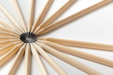 Top view of pencils made of wood lie on a white surface forming an open circle