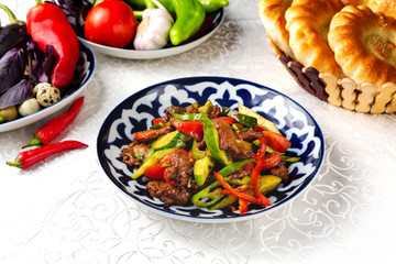 Meat and vegetables in tomato sauce. Ready meal for lunch. Traditional oriental dish. On a plate on a table in a restaurant.