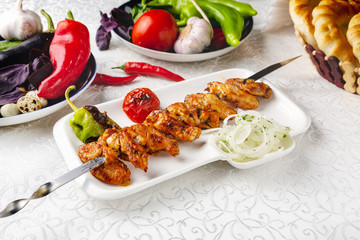 Meat skewers, beef skewers, lamb skewers, oriental lunch, fresh vegetables. On a plate on a table in a restaurant.

