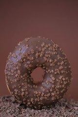 Chocolate donut on grated chocolate on a bright brown background.Baking and sweets. Sweet  dessert.Donut with chocolate icing and chocolate chips.