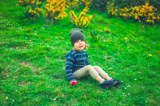 Little preschooler sitting on grass in nature
