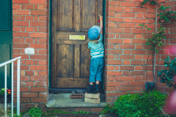 Preschooler standing on bricks to unlock front door