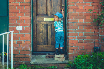 Preschooler standing on bricks to unlock front door