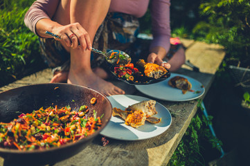Woman dishing salad and chicken outdoors in garden