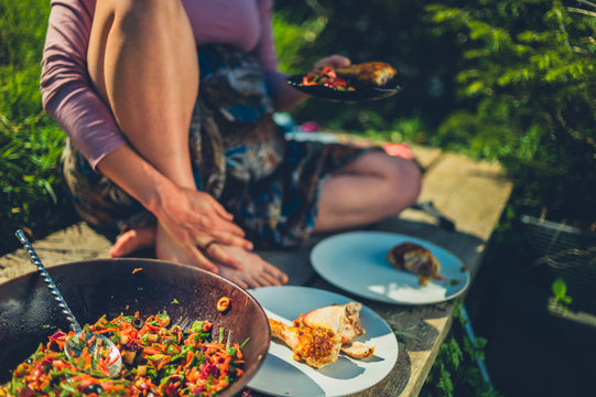 Woman dishing salad and chicken outdoors in garden