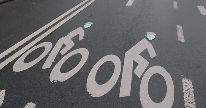 Camera Tilt Down From Person Riding Bike To Road Surface — Painted Bike Symbols Wearing Surgical Masks, Central Park, New York City