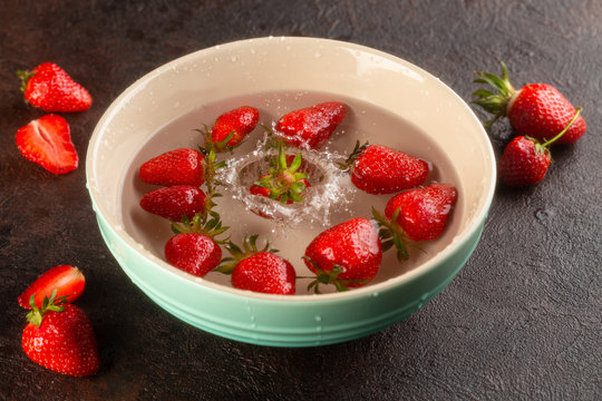 Washing Process Of Fresh,ripe Strawberries In Water In Ceramic Plate.Close Up.Splash Of Water.