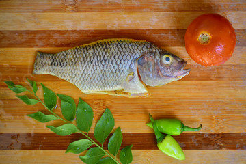 Fresh fish meat cleaned with turmeric, prepared for baking in the oven with herbs and seasoning on a wooden board. Healthy sea foods.