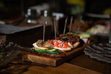 Small sandwiches with cucumber, herring and red caviar in a restaurant serving on skewers