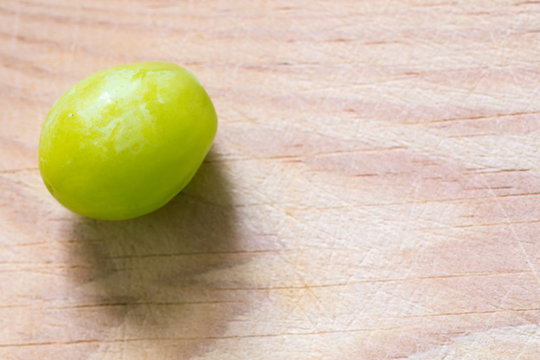 Una uva verde y jugosa sobre una tabla de madera