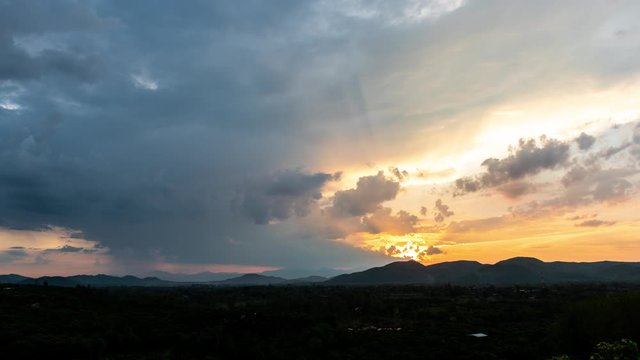 Time lapse-rays light of sunset and rain above the hills (zoom shot)