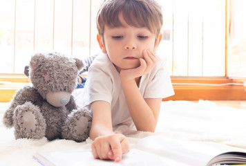 Concentrated boy reading story with his bear. Concept reading, education, relaxation