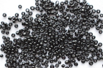 Black beads scattered on a white background.