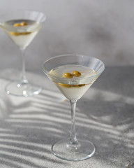 Martini cocktail with green olives. Closeup glass of martini dry cocktail with olives.