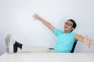 Calm smiling Young Asian Man relaxing at comfortable office chair hands behind head, happy man...