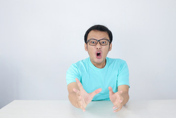 Wow and shocked face of Young Asian man with open hand gesture. Advertising model concept with blue shirt.