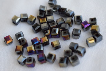 Square black beads with iridescence on a white background.