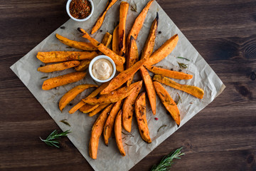 A top down view of spicy sweet potato fries on parchment paper against a dark background.