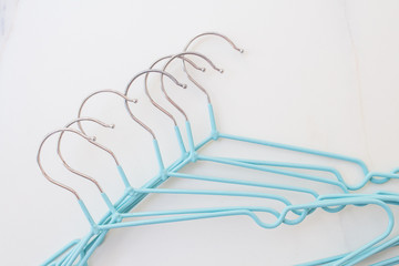 Modern blue hangers on white marble. Fashion blogger concept updating wardrobe for summer season. Minimalism