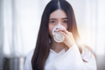 Closeup on Asian young woman drinking milk, selective focus