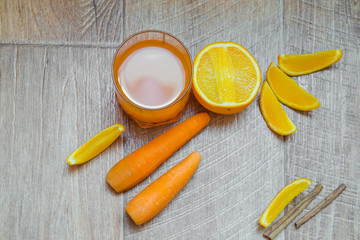 Orange and carrot juice. Carrot juice. Healthy food, healthy drink. Orange juice in a glass and next Orang, peeled carrots. healthy eating for breakfast. Wood background