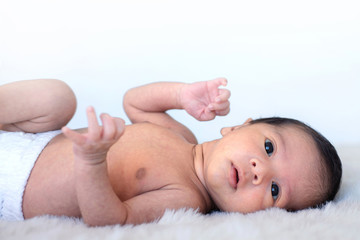 Asian little baby laying on back on white fur, white background