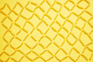 Pattern of pasta on a yellow background. The view from the top.